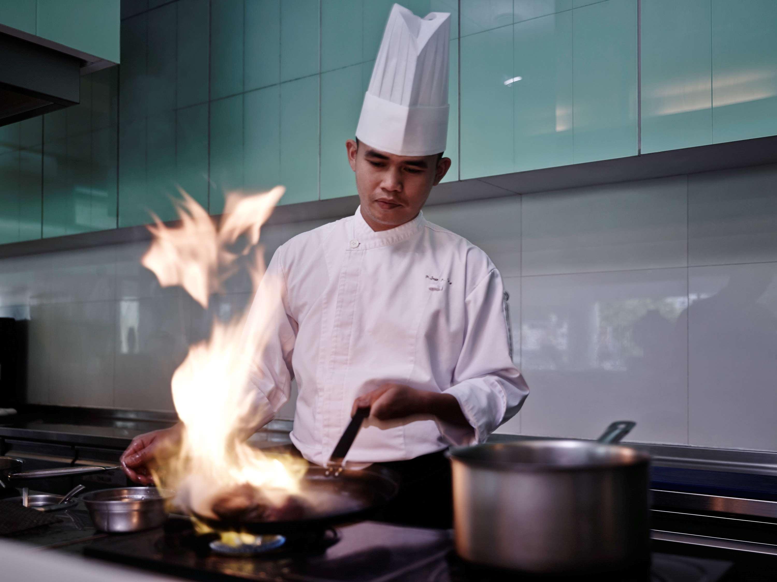 Pullman Kuching Hotel Exterior foto A chef cooking with a flaming wok